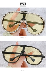 Detail view of oversized luxury aviator sunglasses with rhinestone rim and yellow lenses