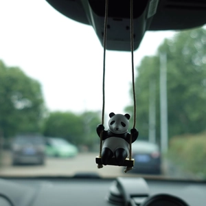 Creative panda swinging car ornament hanging on the rearview mirror with a blurry background