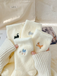 Detail of four pairs of thick thermal white socks with cute animal embroidery on fuzzy fabric