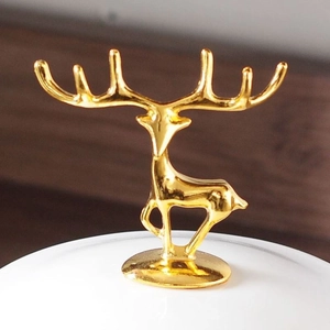 Detailed close-up of a golden zinc alloy deer figurine on a white ceramic lid