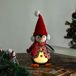 Close-up of glowing penguin gnome plush with LED light and red knit holiday accessories