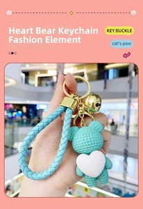 Detail of mint green resin bear keychain with white heart, golden bell and braided strap