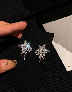 Macro shot of silver star fringe earrings with sparkling pavé zircons held by hand