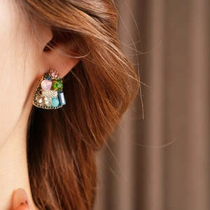 Close-up of vintage geometric stud earring with colorful crystals on model ear