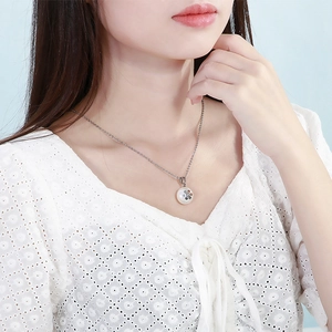 Detail of a silver necklace with a white pearl flower pendant worn by a model