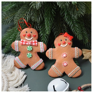 Detail of gingerbread man and woman Christmas ornaments with red bows and hanging ropes