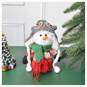 Detail of plush snowman ornament with grey owl hat and green scarf for Xmas decor