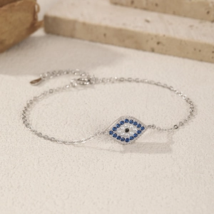 925 sterling silver evil eye bracelet with blue gems on a natural stone background