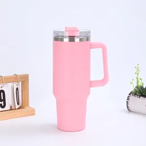Pink 40oz insulated tumbler with handle and straw on a desk with a wooden calendar