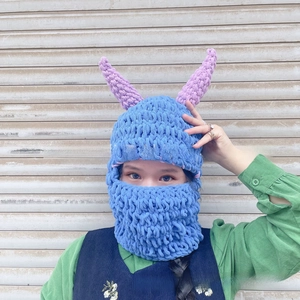 Detail of blue knitted balaclava with purple devil horns and thick woolen texture