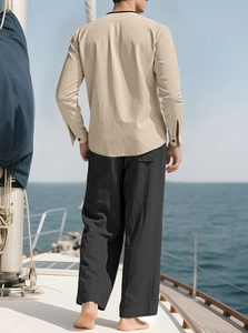 Rear view of men's beige linen shirt and black loose pants on a yacht deck with sea background