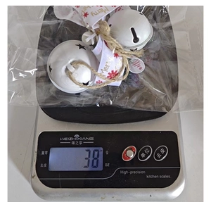 Detail shot of a 38g Christmas metal bell with ribbon on a scale for weight display