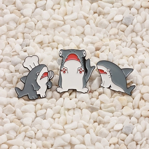 Detailed trio of shark enamel pins featuring chef and quirky poses on white stones