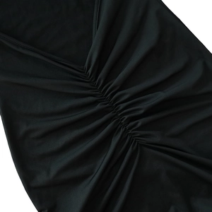 Close-up detail of the ruched V-neckline on a black bodycon maxi dress with pleated texture