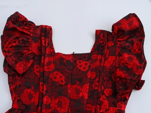 Detail of floral jacquard fabric with square neckline and ruffled cap sleeves on black dress