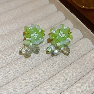 Macro detail of green beaded flower earrings with iridescent teardrop crystals