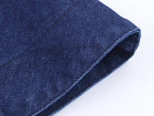 Close-up of deep blue denim fabric texture and precise stitching on the cape top edge