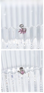 Macro detail of silver titanium steel earrings with pink zircon swan and heart designs