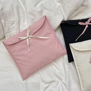 Dettaglio di custodie per laptop imbottite con fiocchi nei colori rosa, nero e beige