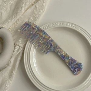 Macro shot of wide-tooth acetate hair comb with colorful tortoiseshell pattern on white plate