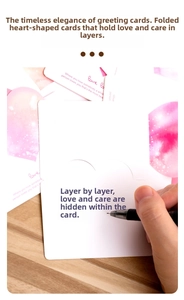 Close-up of hand writing message in a pink watercolor heart greeting card