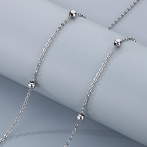 Minimalist silver titanium steel station chain necklace with delicate beads on blue stand