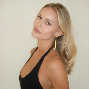Elegant 18k gold curved long teardrop earrings worn by model in a minimalist style