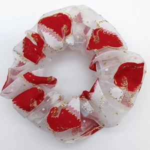Close-up of white mesh scrunchie with festive red patterns and sparkling gold glitter
