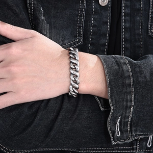 Close-up of a bold silver stainless steel Cuban chain bracelet on a model's wrist