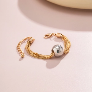 Close-up of gold snake chain bracelet with silver sphere bead and lobster clasp detail