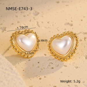 Macro detail of heart earrings with baroque pearls and golden beads on stone