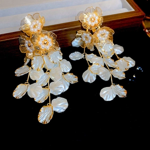 Makroaufnahme goldener Vintage-Ohrringe mit Perlen und weißen Schichtblüten