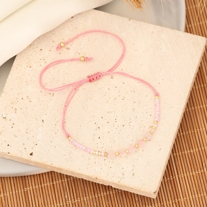 Macro shot of pink natural stone beads and golden spacers on adjustable woven bracelet