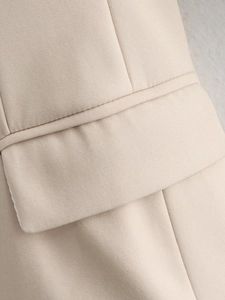 Close-up of premium stitching and twill fabric texture on a beige oversized blazer