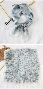 Detailed view of light blue silk scarf with floral patterns shown tied and flat
