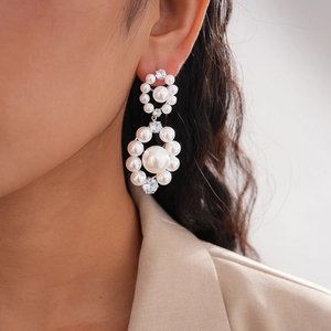 Macro detail of cluster pearl earrings with rhinestone accents shown on a model
