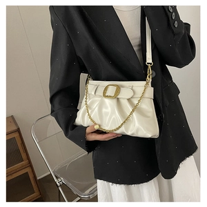 Gros plan sur sac bandoulière crème plissé avec boucle carrée dorée et chaîne en métal