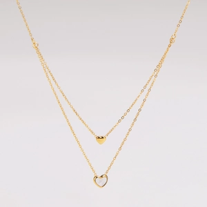 Detail of double-layer gold necklace with solid heart and white shell heart pendant