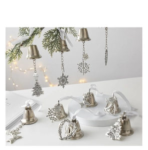 Close-up of silver Christmas bells with snowflake and reindeer charms on pine branches