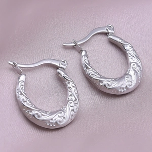 Detailed macro view of silver hoop earrings featuring intricate vintage floral engravings