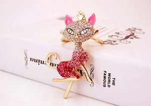 Detail of a golden cat keychain with pink rhinestones and enamel on a book background