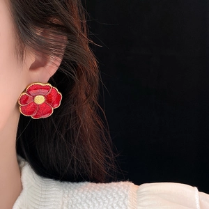 Detail of vintage red flower earring with gold metallic edges on a female model