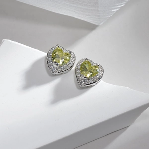 Macro detail of heart-shaped yellow zircon earrings on minimalist white stone display
