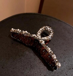 Close-up of amber shark hair claw clip with white imitation pearls and sparkling rhinestones