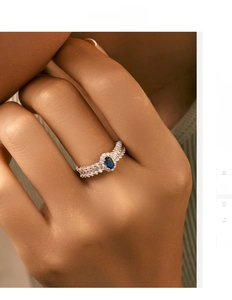 Close-up of S925 silver ring featuring an oval blue gem and wavy diamond pavé on finger