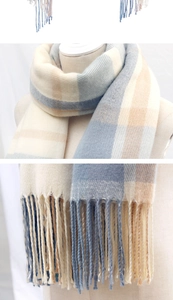 Close-up of soft knit scarf featuring a beige and blue plaid pattern with fringe edges