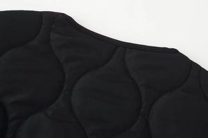 Détail macro de la veste matelassée noire avec piqûres gourde et col rond