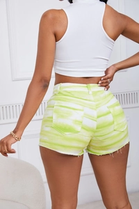 Detail view of tie-dye denim shorts featuring yellow and white texture and raw hem