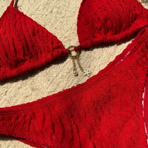 Detailed macro shot of red textured bikini with pearl starfish pendants and metal ring
