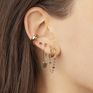 Close-up of golden ear cuff and chain earring with rainbow gemstones on female ear
